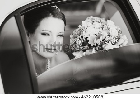 beautiful bride with bouquet sitting in limo, wedding picture in sepia
