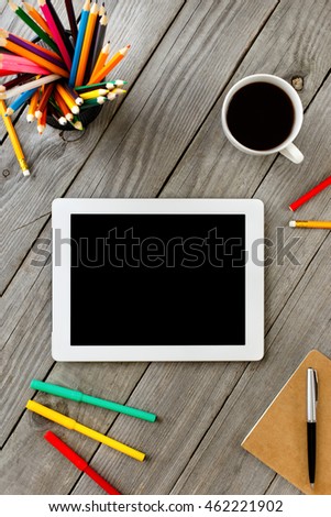 White Tablet With Blank Screen On Wooden Desktop in a home office With Colored Pencils  And Cup Of Coffee, Top View