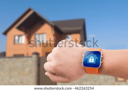 Smart watches with home security app on a hand on the building background