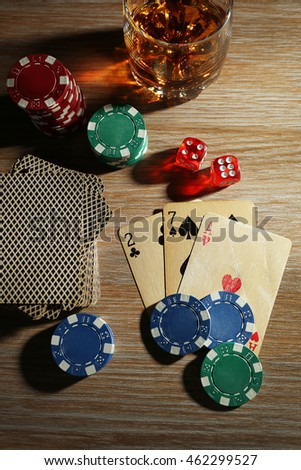 Set to playing poker with cards and chips on wooden table, top view