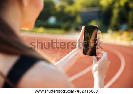 Cropped image of a young sportswoman making selfie photo on mobile phone after training outdoors