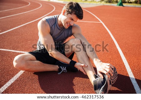 Young male runner suffering from leg cramp on the track at the stadium Royalty-Free Stock Photo #462317536
