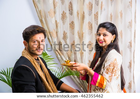 Indian good looking young brother and sister celebrating Raksha Bandhan / Rakhi  festival or on Bhai dooj/Bhau-Beej with Poja Thali, sweets, gifts or taking selfie pictures - Season's Greeting Card
