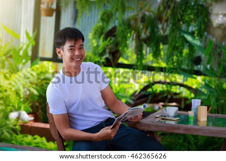 smiling asian casual man reading magazine 
