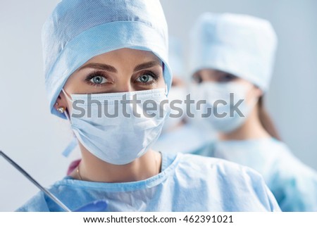 Close-up portrait of young female surgeon doctor at operation theater. Group of surgeons at work. Healthcare, medical education, emergency medical service and surgery concept
