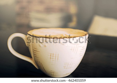 Coffee in cup with sunlight on wooden table.