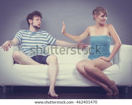 Bad relationship concept. Man and woman in disagreement. Young couple sitting on couch at home having quarrel, offended wife and unhappy husband