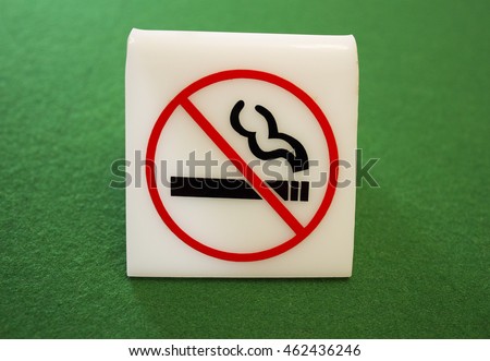 A bright, true to life photograph of a no smoking sign on a green felt background