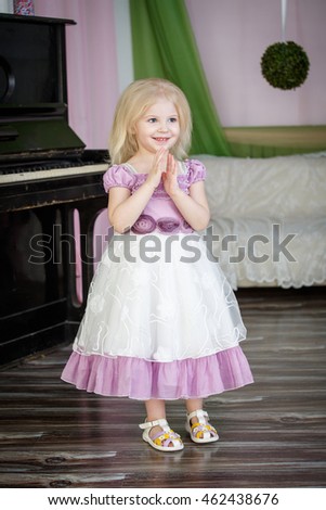 Portrait of a little girl with a beautiful dress near the piano