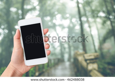 Smart phone with  black screen in hand on blurred in forest background