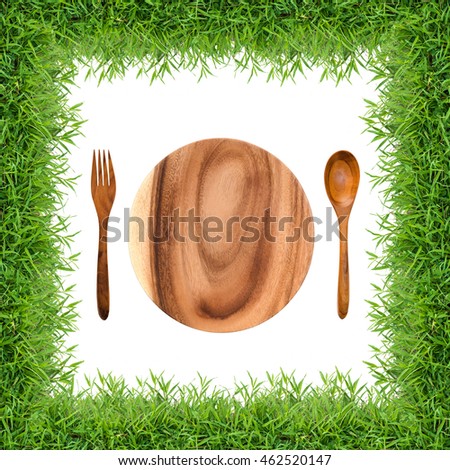 Top views kitchenware set of wooden dish, fork and spoon in green grass frame isolated on white background.