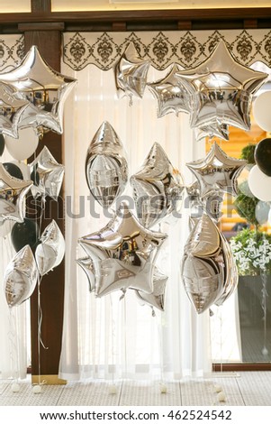 Silver baloons hang under brown ceiling