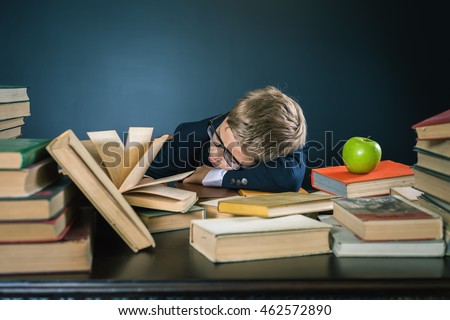 School boy sleeping at the table with many books and one green apple. Many homeworks or exam - is stress for little kids. Motivate your child to study a boring subject. Student. Pupil studying