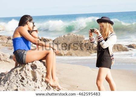 Three young women taking photographs on smartphone on beach, Malibu, California, USA