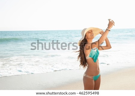 Young woman taking selfie on smartphone on beach, Malibu, California, USA