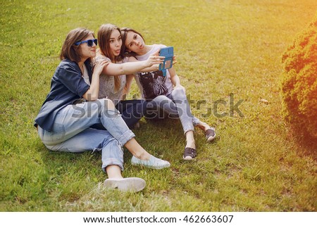 three beautiful girls walking in the park and take pictures on your phone