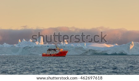 Tourists on the boat take pictures of the icebergs in the Disko Bay, Greenland. The source of these icebergs is the Jakobshavn glacier due to global warming and catastrophic thawing of ice