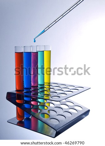 Close up of test tubes filled with color liquids and a pipette.