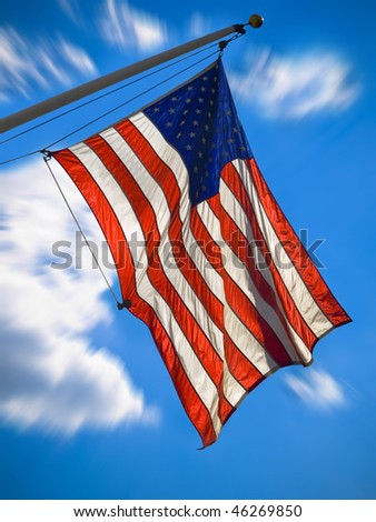 An american flag waving over a blue sky. Zooming effect.