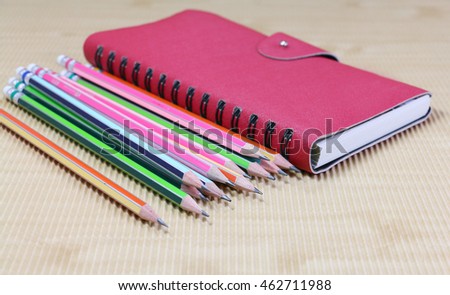 group of pencil and red book  on wooden desk