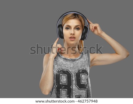Portrait of blond female in earphones isolated on grey background.