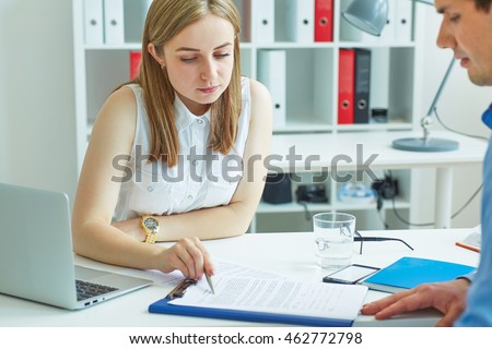 Young female employee of the staffing agency helps fill out the form to the male job seeker. Business, office, law and legal concept