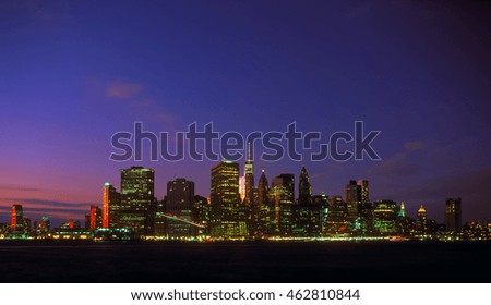 New York City skyline at night with blue sky and illuminated buildings.
