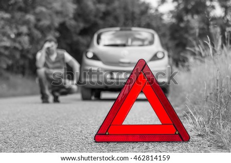 Broken car on the road and unhappy driver with red warning triangle - black and white concept