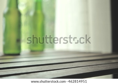 Blurry of 2 beer bottles green color, foreground is wooden table, abstract of green color blurred, vintage color tone and soft focus light background