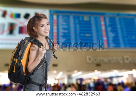 Happy asian woman travel at airport terminal. Flight schedule display blur in the background.