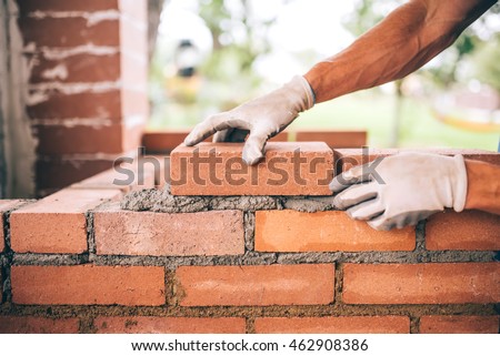 professional construction worker laying bricks and building barbecue in industrial site. Detail of hand adjusting bricks Royalty-Free Stock Photo #462908386