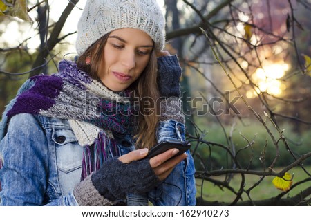 Cute young woman in park in autumn, listening to music, colorful, sunset background