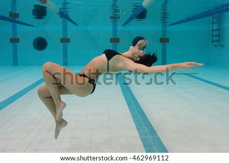 Woman portrait wearing black bikini inside swimming pool.