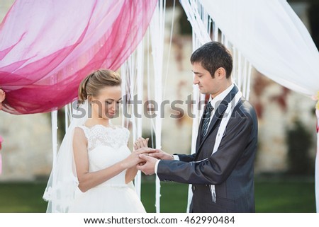 happy groom gives his wife a gold ring