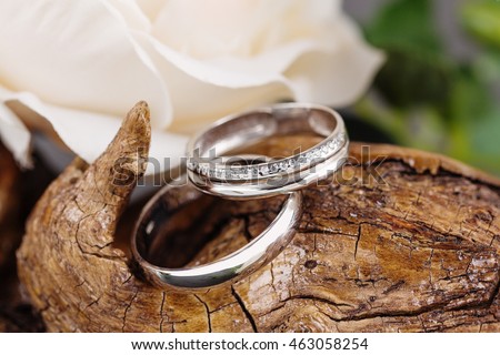 Two white golden wedding rings on wood background. Bride ring with diamonds. Shallow focus. Rustic concept