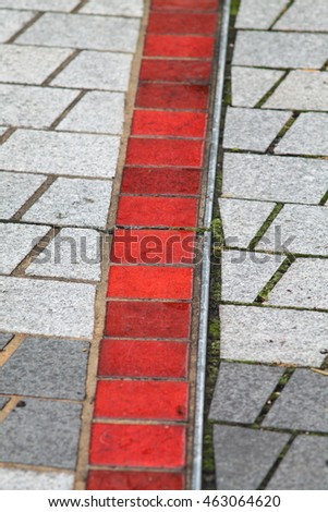 Stone street pavement with red line made with ceramic tiles. Fragment of street pavement with red ceramic line.
