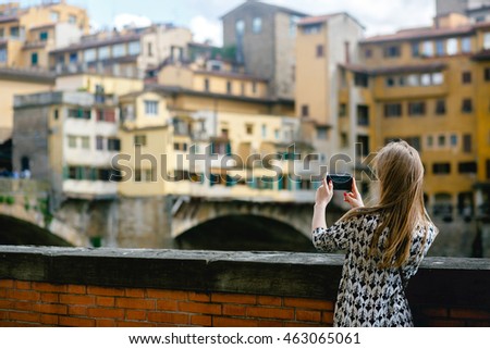 Girl takes a picture of an old city on her phone