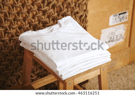 Many folded white basic cotton t-shirts presented in rustic interior Royalty-Free Stock Photo #463116251