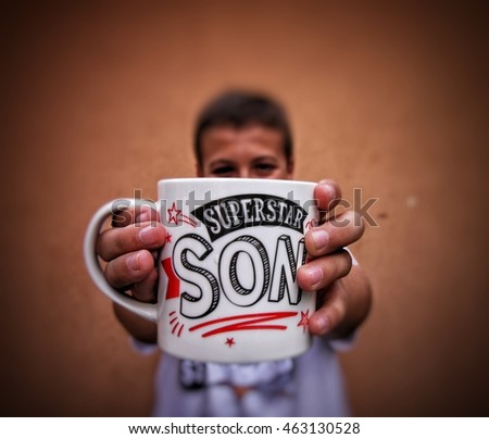Young boy holding a mug with superstar son quote
