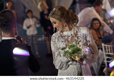 Gorgeous bride looks over her shoulder standing with a wedding bouquet in a restaurant