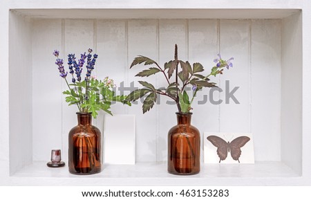 Shelf with lavender and geranium in old pharmacy bottles.