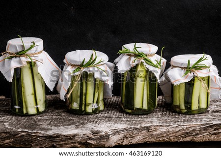 Marinated zucchini with rosemary in jars on wooden table