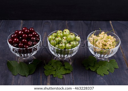 White currant, green gooseberry, cherry, in a bowl on a table