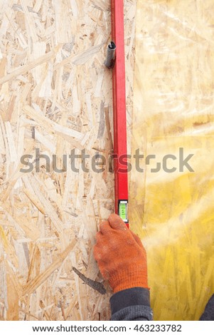 Builder ensuring that a wall is vertical holding a builders level 