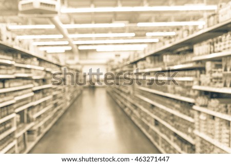 Blurred image of supermarket aisle and shelves. Wide perspective view of supermarket aisle and people shopping. Defocused blurry background with bokeh light in store. Business concept.