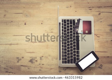 Top view with Credit card and laptop and smart phone on wooden desk in office with copy space. vintage filter effect.release concept.
