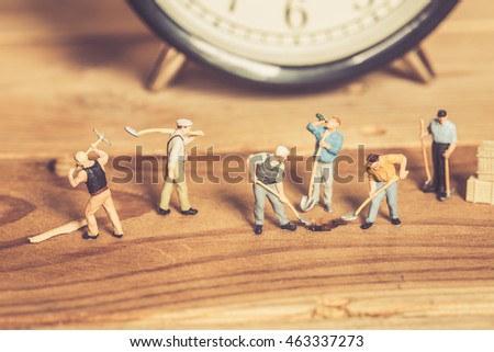 miniature worker people hard teamwork on working digging hole on wood background vintage color tone for postcard.