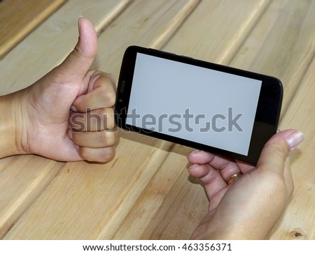 Girl with phone in hands on wooden table, top view .The concept of good phone software, phone security, reliability of the shop - girl showing thumbs up. Layout.