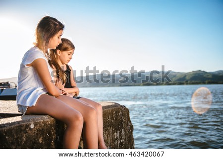 Girl comforting her sad friend on dock