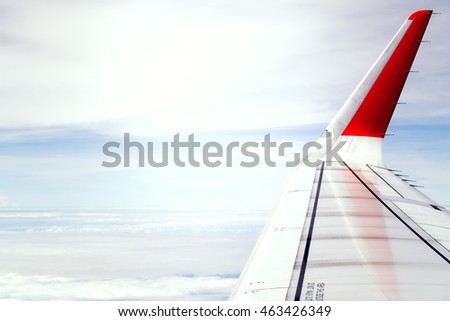 Wing of an airplane flying above the clouds Royalty-Free Stock Photo #463426349